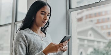 A concerned woman looking at her cell phone