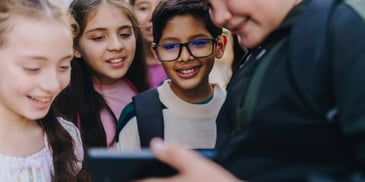 A group of young people gathered around a cell phone