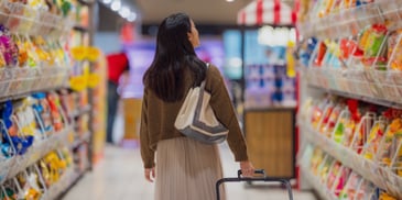 A woman browsing items in a grocery store aisle