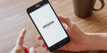 A person holding a phone displaying the Amazon app